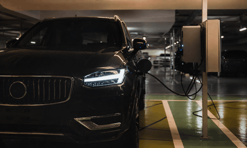 Vehículo eléctrico cargando en un aparcamiento empresarial
